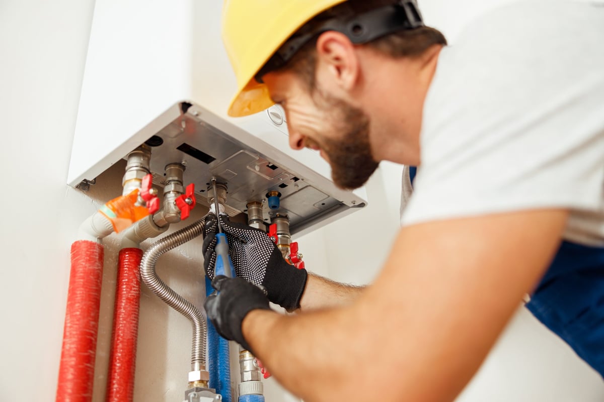 Plumber using screwdriver while fixing boiler