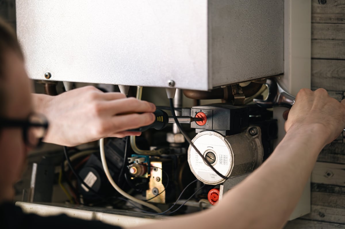 Man repairing heating boiler with screwdriver and spanner